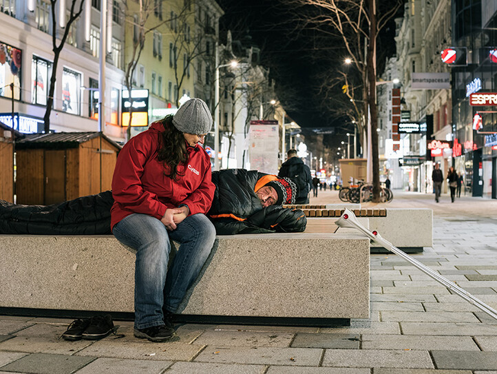 Mitarbeiterin spricht mit Obdachlosem